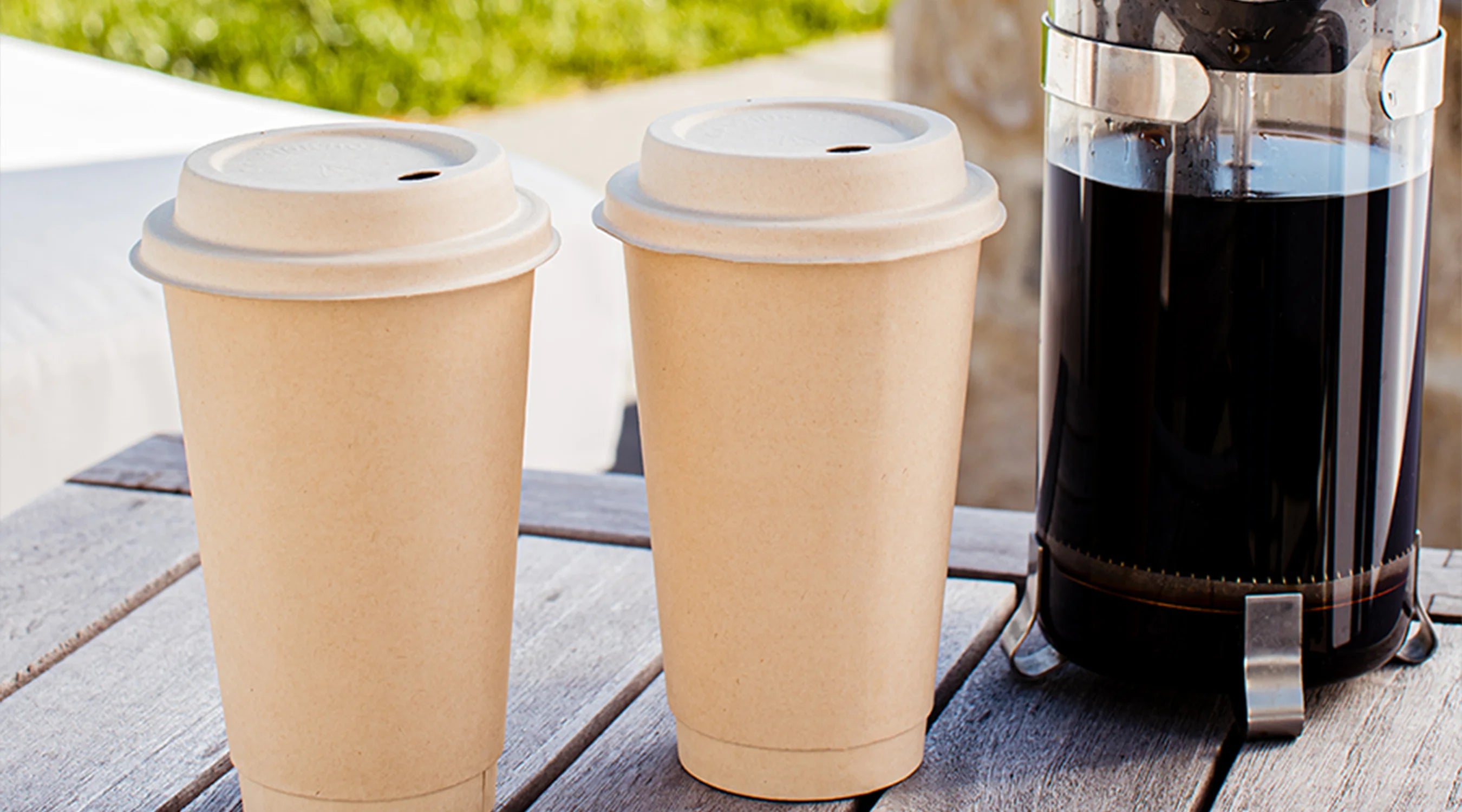 Two compostable hot cups beside a coffee maker