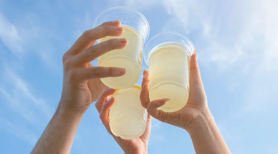 Three individuals proudly display three cups of lemonade, served in compostable cold cups.