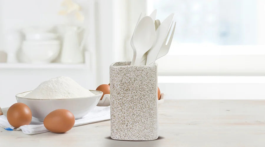 A white ceramic vase filled with compostable cutlery.