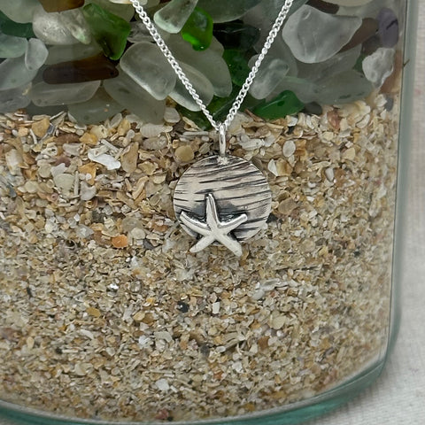 A silver pendant with a rippled texture to represent the marks on the wet sand left by the receding tide with a silver starfish embellishment