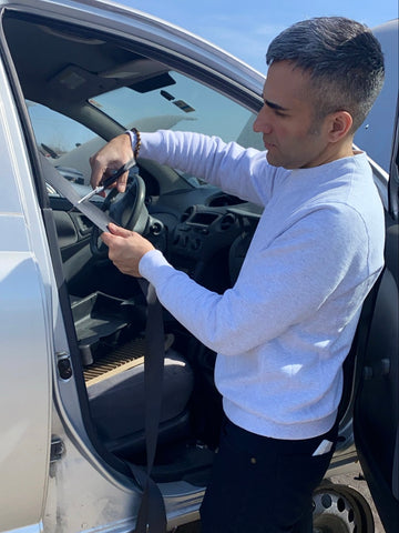 founder of bedi studios, inder bedi, demonstrating how to cut the seatbelt properly for his production