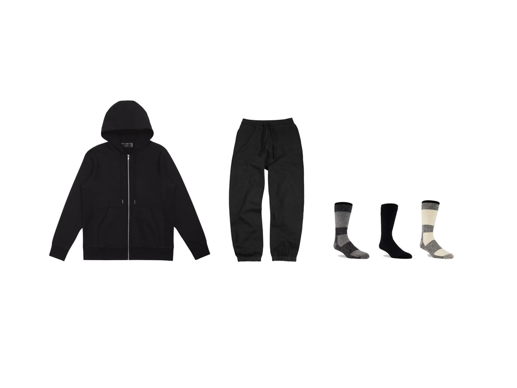 flat lay on a white background displaying a black hoodie, black joggers and three socks (grey, black and natural) from left to right