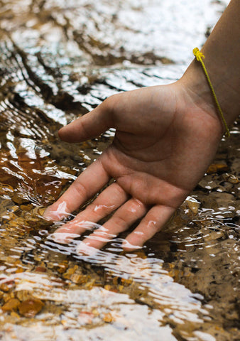 Eine Hand spürt das Wasser in einem Bach