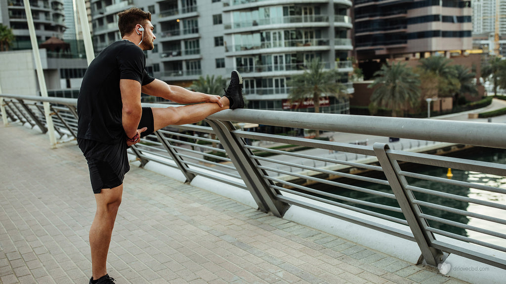 healthy man with headphones stretching outside before a run through the city