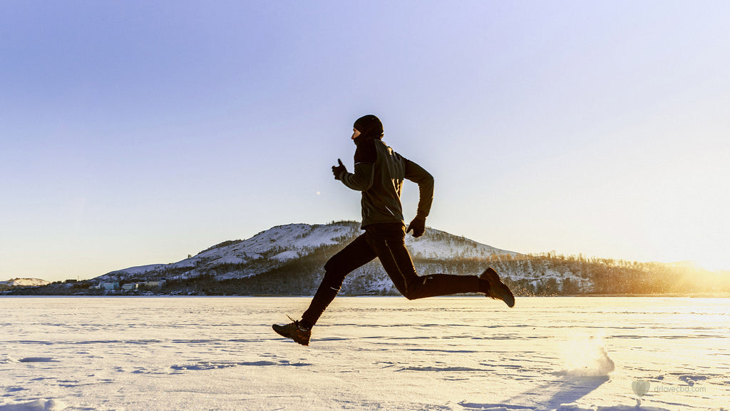 outdoor photo of healthy man running across the snow during a bright sunny winter day