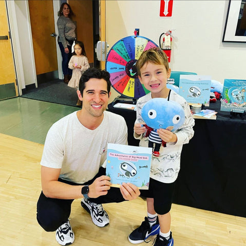 David Bradley, author of Big Head Bob, is posing with a young child with a Big Head Bob plushie and book.