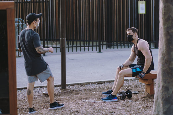 two guys in a park wearing face masks