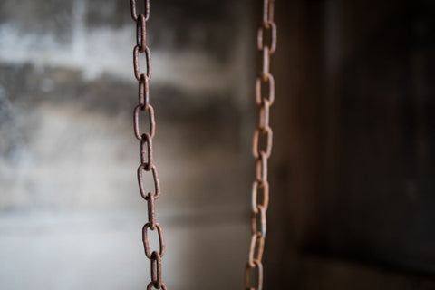 A chain hanging with significant copper tarnish