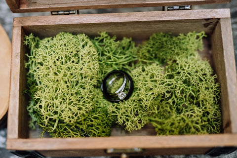 Two rings sit inside of a jewelry box with moss
