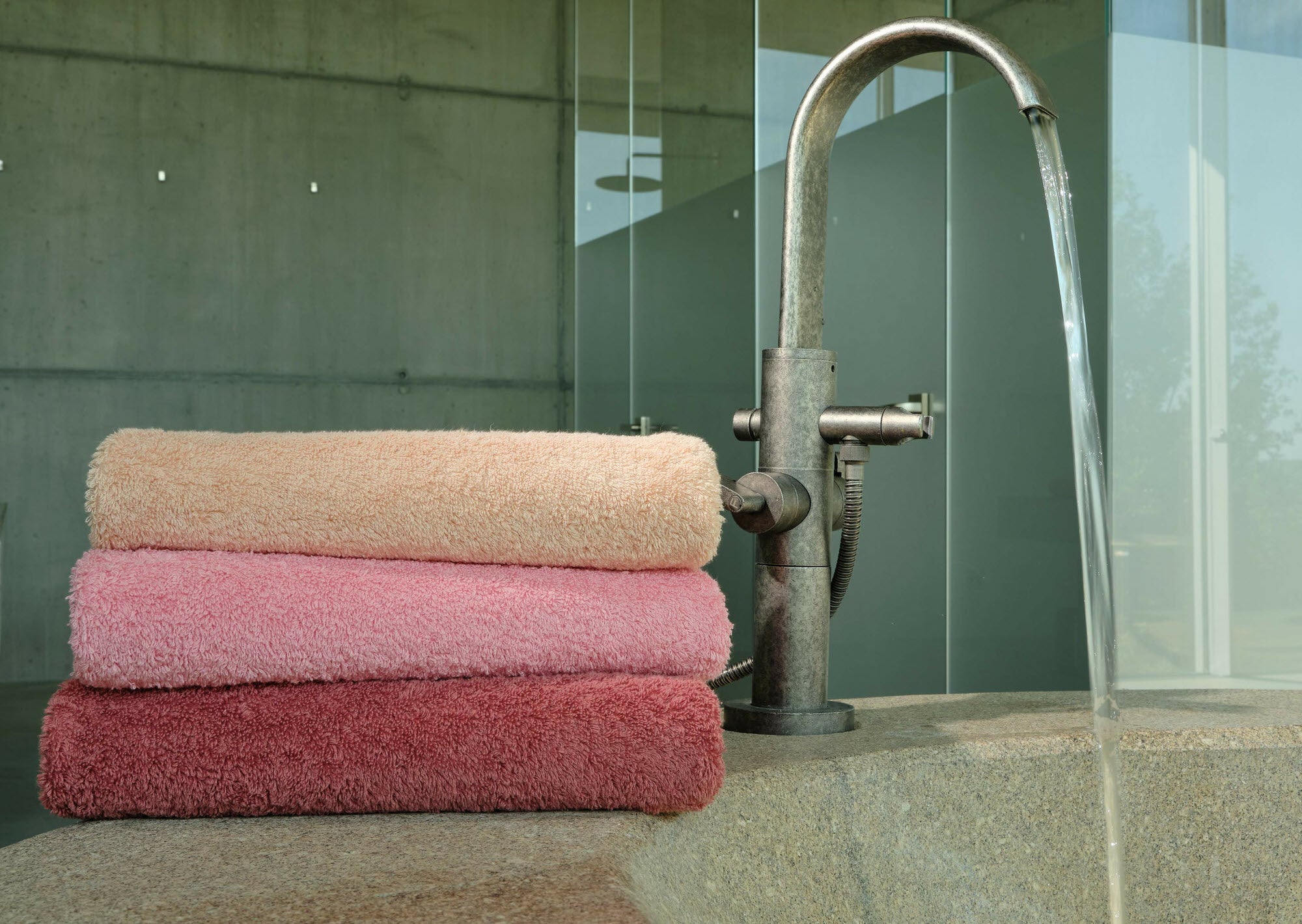 Abyss Super Pile bath towels stacked on the edge of a tub