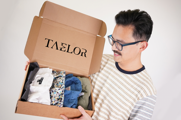 A male model opens a box from Taelor with different shirts in it