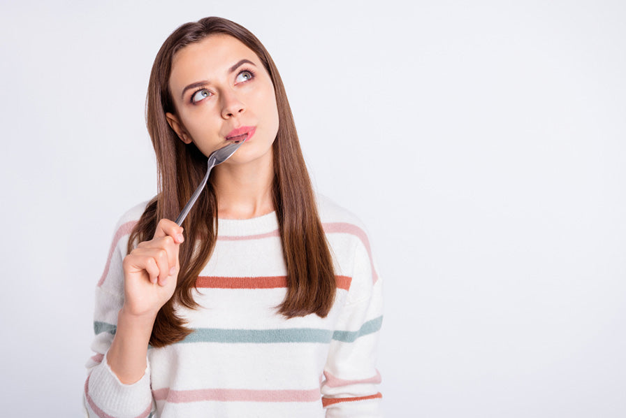 a woman with a spoon in her mouth looking up contemplatively