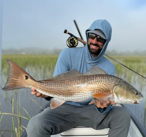 Fisherman catching a redfish in the Angler Crossover Bamboo Hoodie.