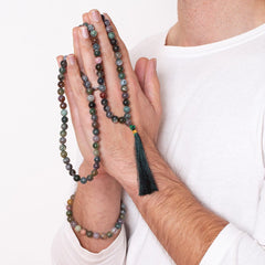 man with Ambarya bloodstone mala beads wrapped arounded his hands and wearing Ambarya mala bead bracelet