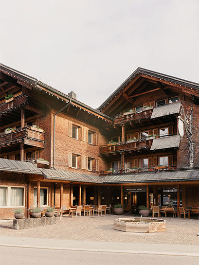 Außenansicht vom Hotel Post Bezau mit Blick auf den Haupteingang, die Terrasse, den Brunnen und das Stammhaus