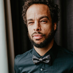 man wearing black shirt and black and gold cork bow tie