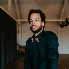 man with black shirt and cork bow tie