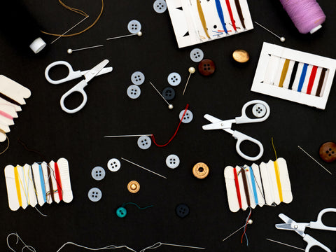 A flat lay image of three pairs of scissors, some colour thread and buttons.