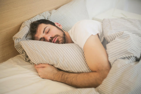 A man asleep in a bed under a white duvet.