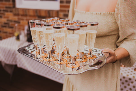 A woman holding a tray of glasses of champagne, welcoming guests
