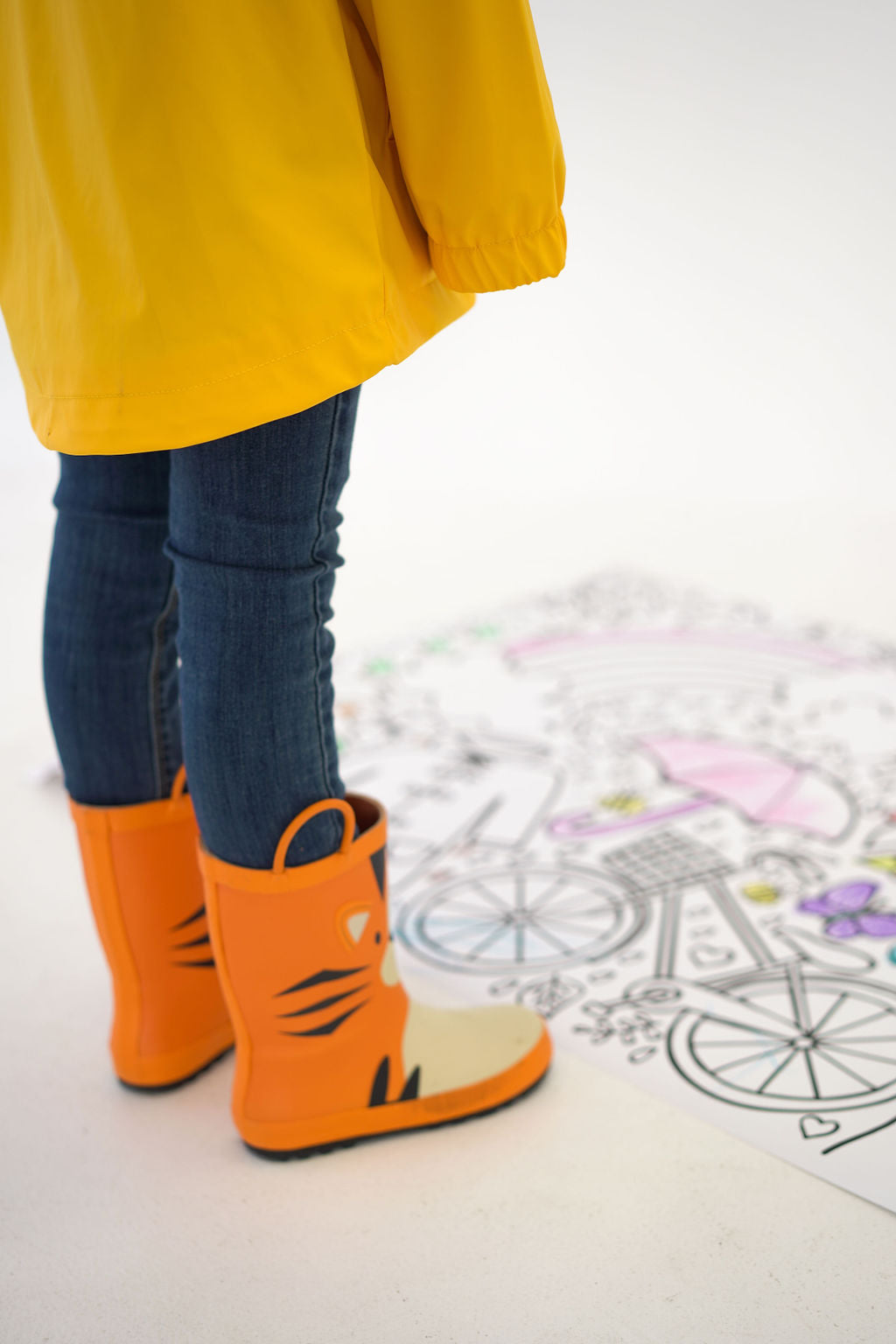 Girl standing with rain boots on looking at a giant coloring banner