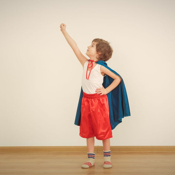 Boy Wearing A Blue Cape and Red Shorts Posing as a Superhero