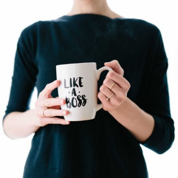 A woman holding a coffee mug that says, "Like a Boss".