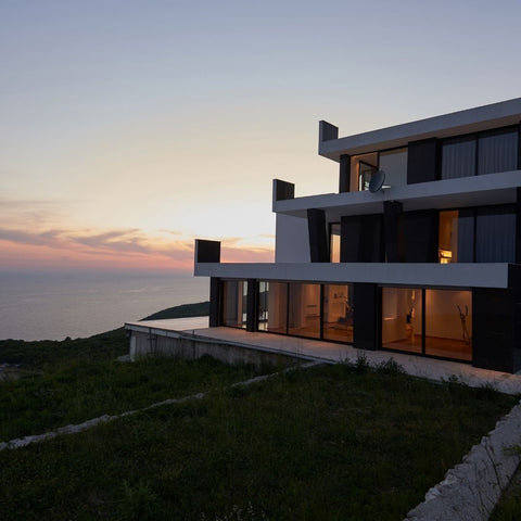 An amazing house along the shore at sunset.