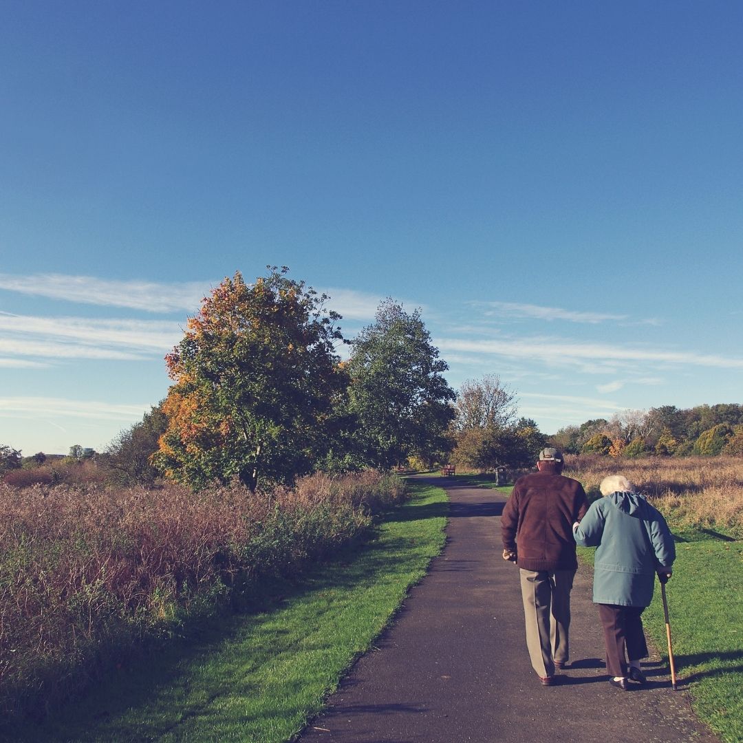 Two people walking on a park trail during retirement.