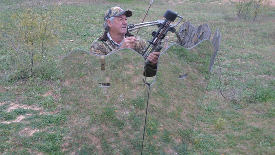 a hunter with a crossbow sitting behind a mirrored ground blind