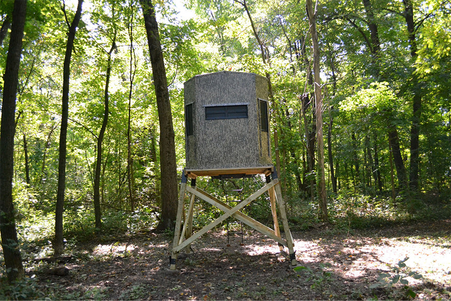 an elevated archery blind set up in the woods