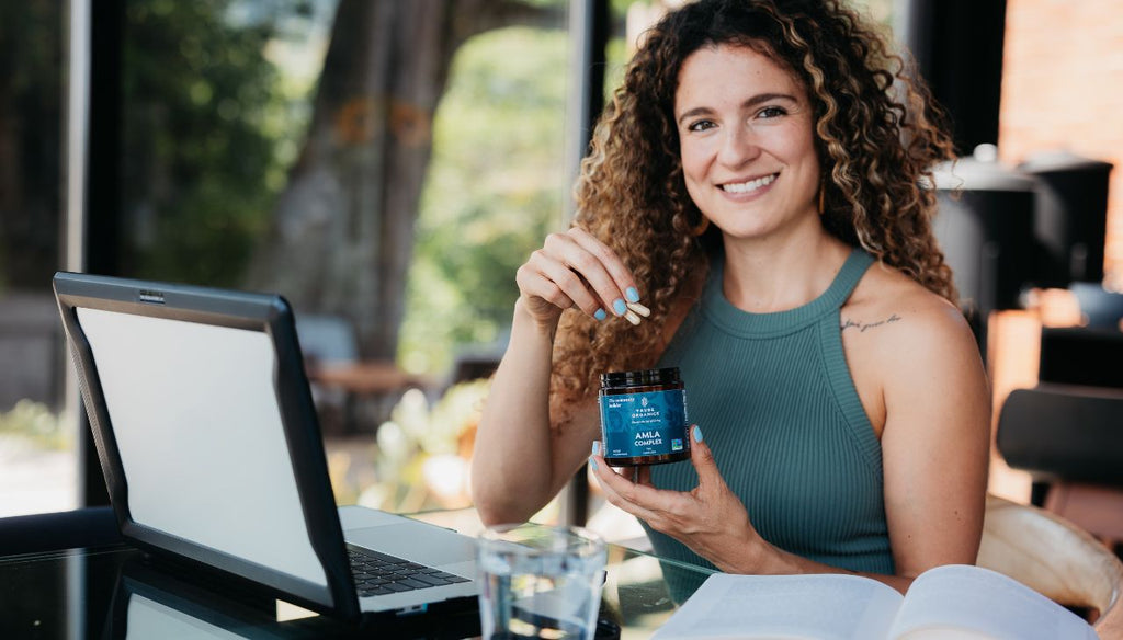 Woman smiling taking her Tribe Organics Amla capsules