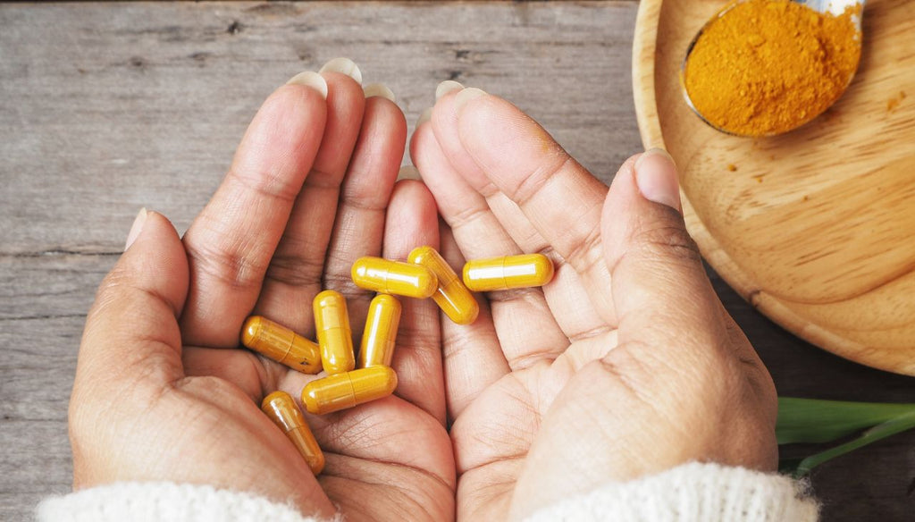 Turmeric capsules in both woman hands