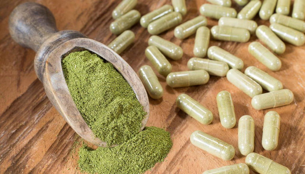 Capsules and moringa powder in a wooden table.