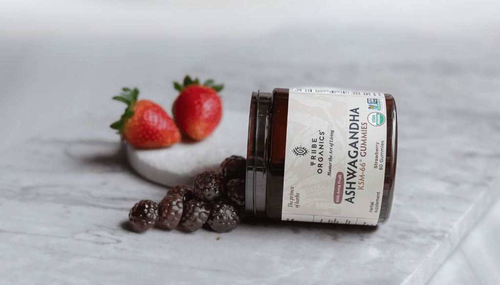 Bottle of Ashwagandha Gummies Tribe Organics on a table with gummies and strawberries