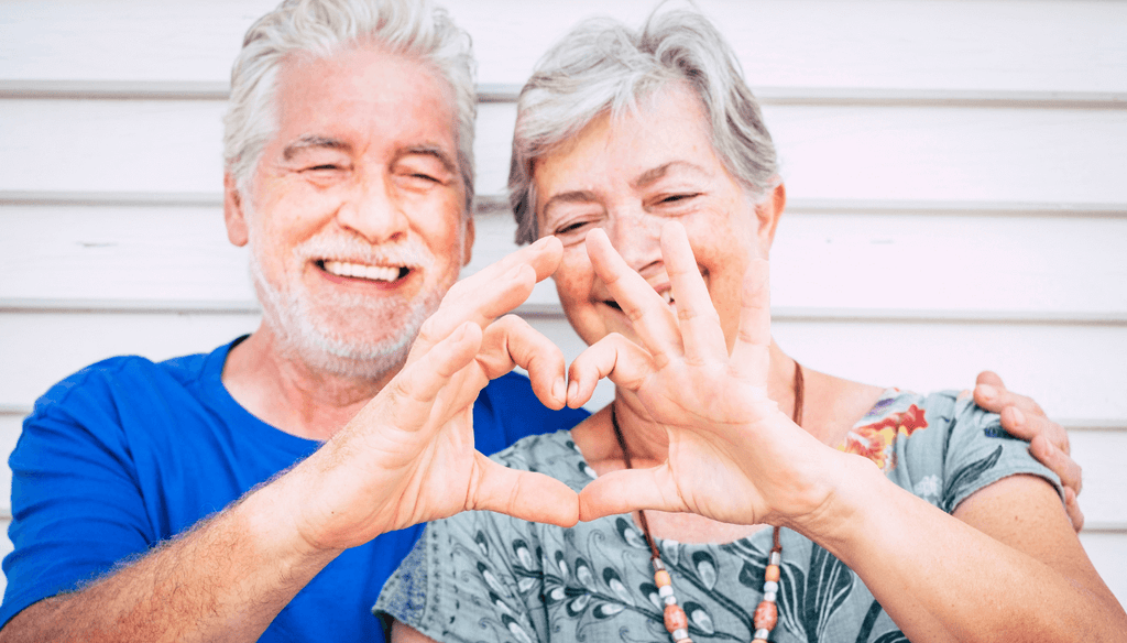 Older couple smiling and doing a heart with their hands
