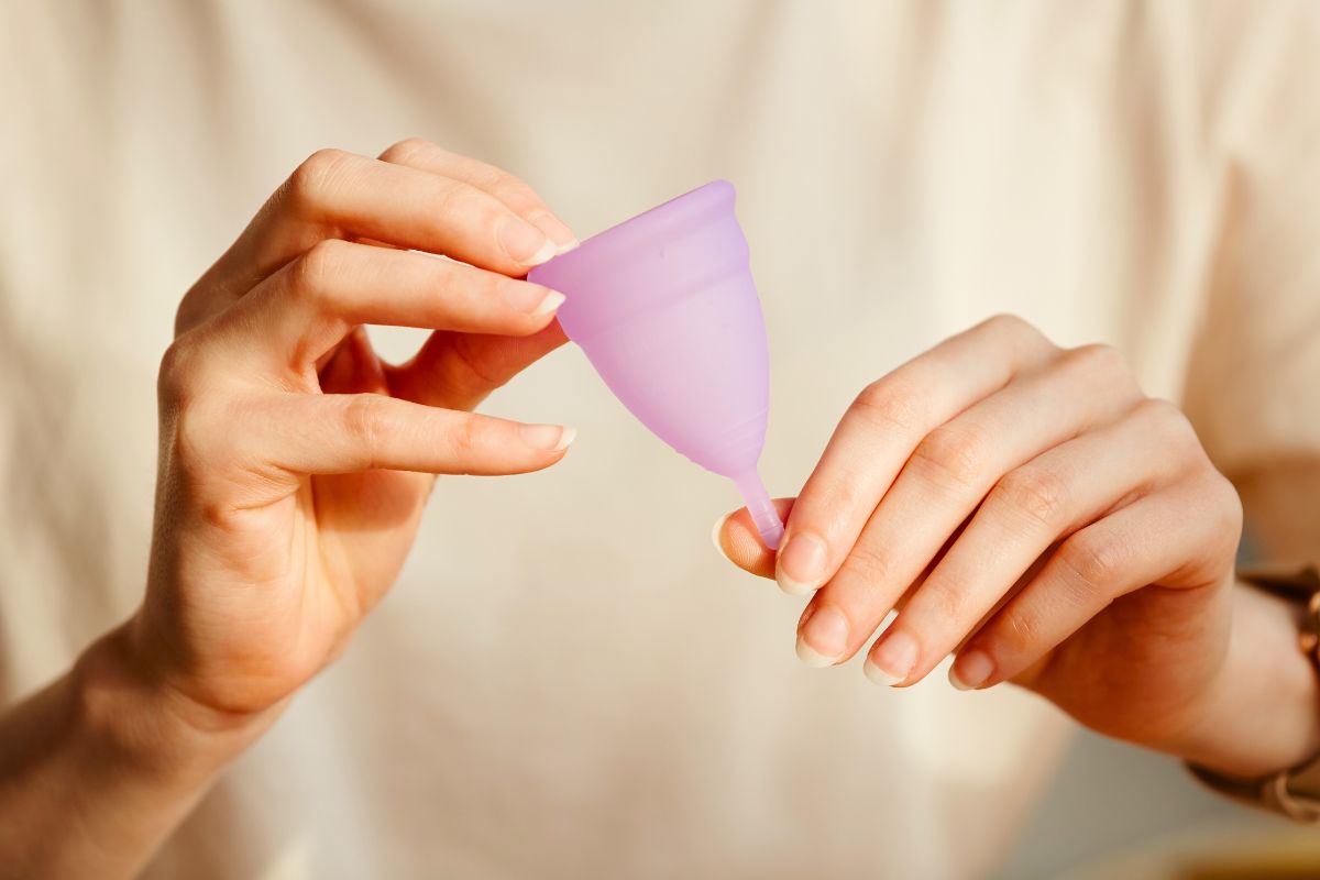 Une femme tient une coupe menstruelle pour se débarrasser des mauvaises odeurs