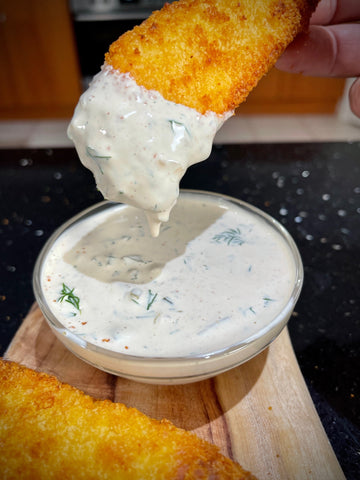 Chicken tender dipping into homemade tartare sauce 