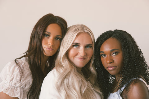 Beige background with a brunette model on the left, blonde model in the middle and African American model on the right.