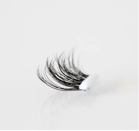 One segment of the WinkClique Eyelash Extensions with a bubble of white adhesive on it.