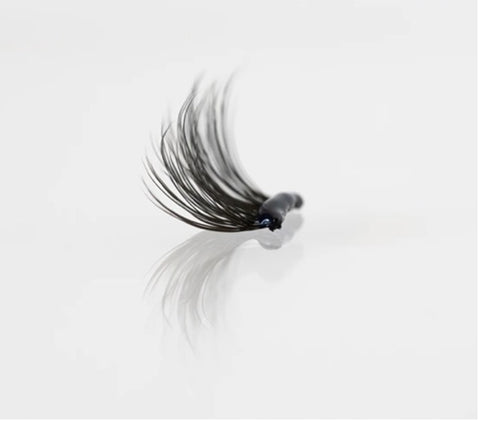 One segment of the WinkClique Eyelash Extensions with a bubble of black adhesive on it.