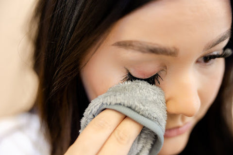 Brunette woman using a WinkClique micro-fiber cloth to remove her diy eyelash extensions.