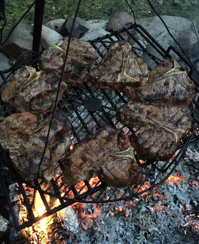 Grilling steaks on a tripod over the fire pit