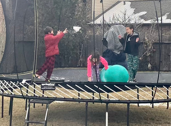 Photo of 3 kids playing in a trampoline in snow