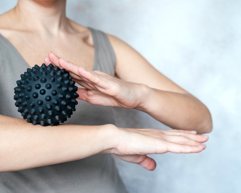 woman using massage ball on arm