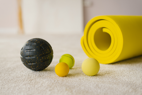 different size massage balls with a yellow yoga mat