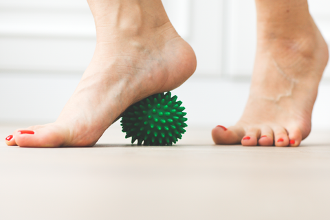 woman massaging heel with spiky massage ball