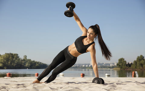 woman working out with weights on sand outdoors