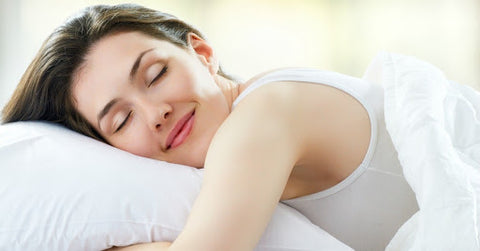 woman smiling while lying in bed on pillow resting