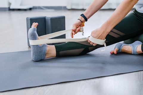 stretching leg on yoga mat with strap